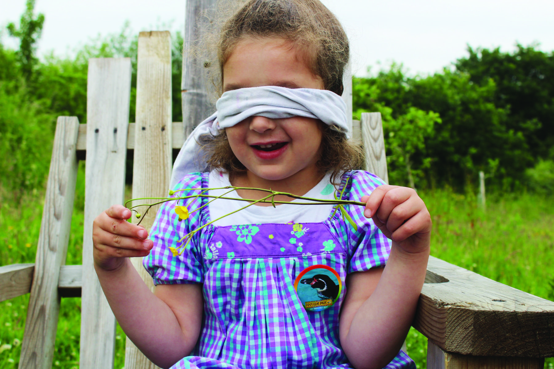 Child blindfolded holding a flower