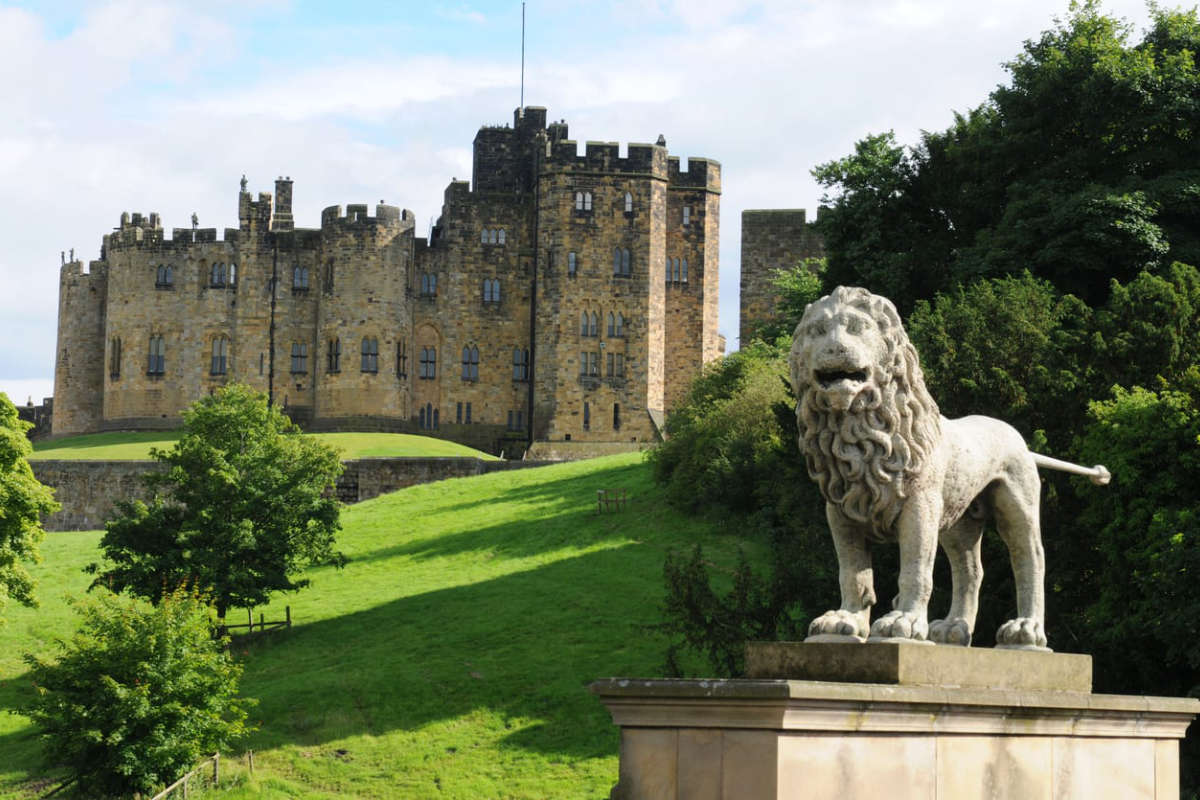 Lion statue in front of a large castle