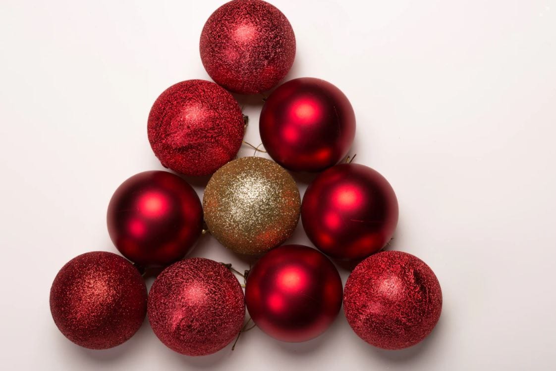 Stack of red Christmas baubles with a gold bauble in the middle