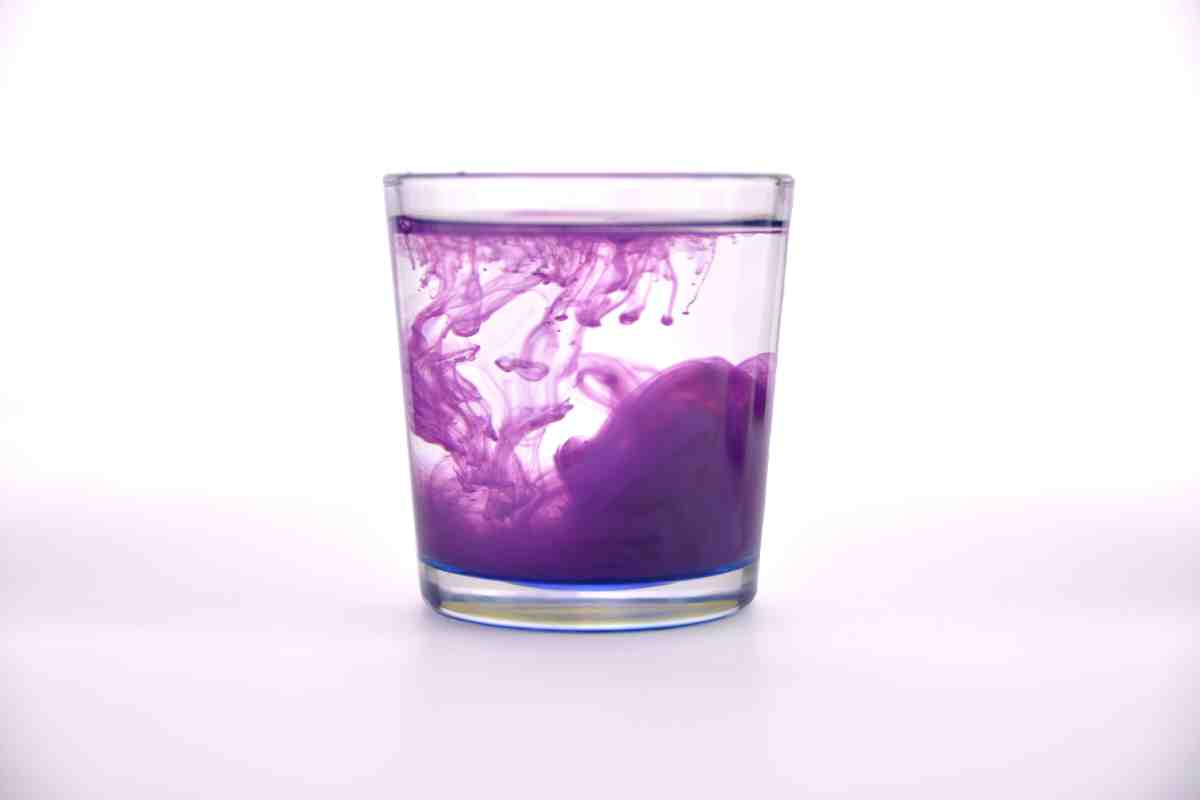 Glass with water with purple paint