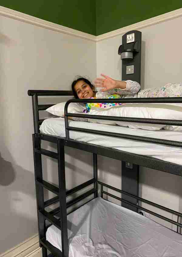 A girl lay in a bunk bed waving 