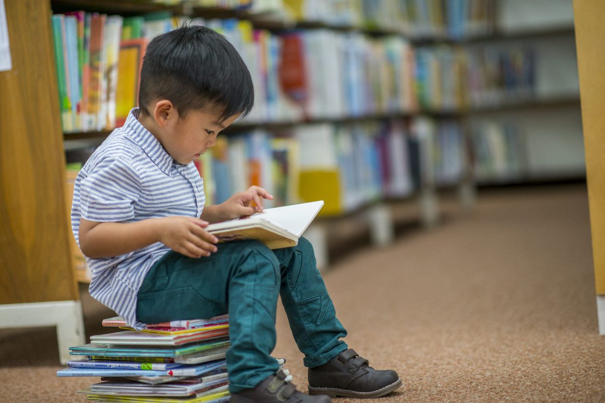 Child reading a book in a library