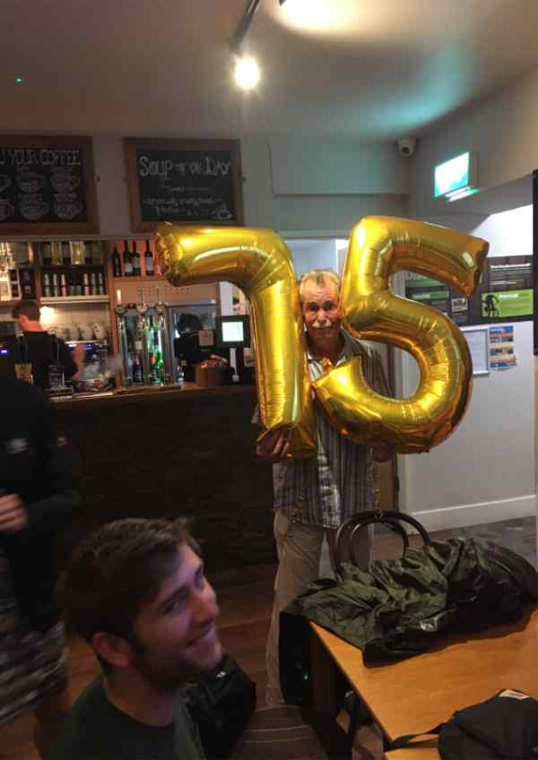 A man holding his 75 balloons at a party
