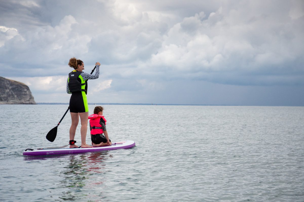 Adult and child paddleboarding at sea