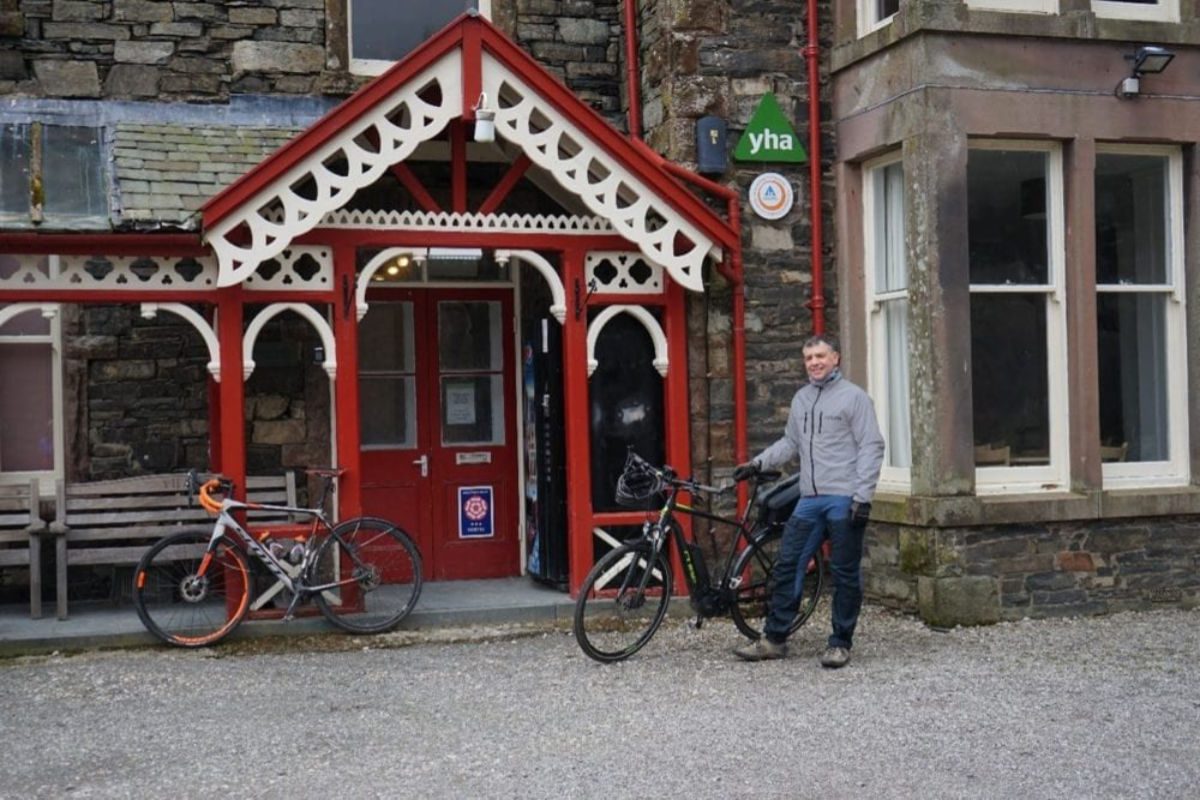 Cyclist standing outside a YHA hostel
