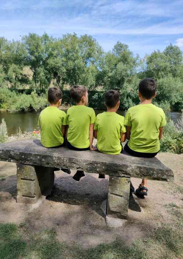 Four boys sitting on a bench outside 