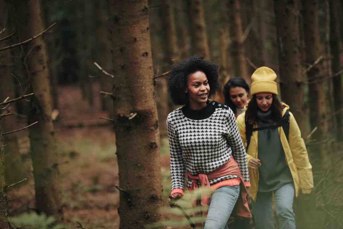 Group of diverse young female friends in outdoor gear hiking along a trail together in the woods