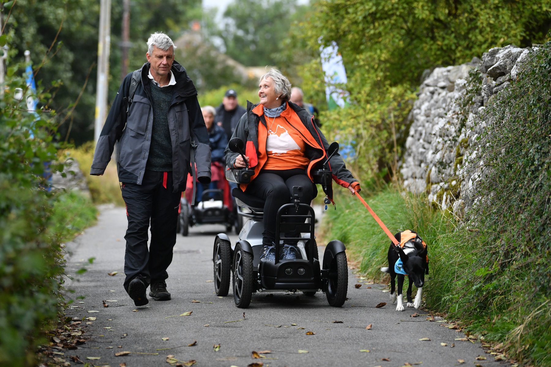 Wheelchair user with a dog walking through countryside