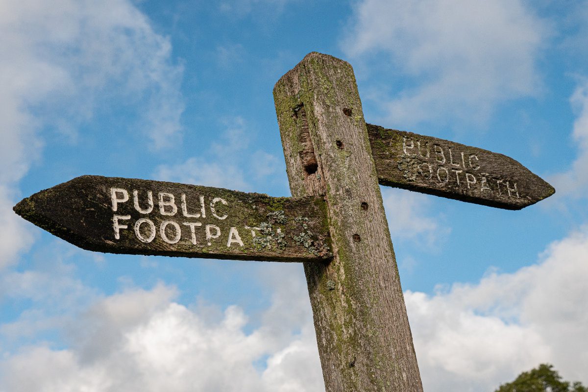 Public footpath wooden sign against blue sky
