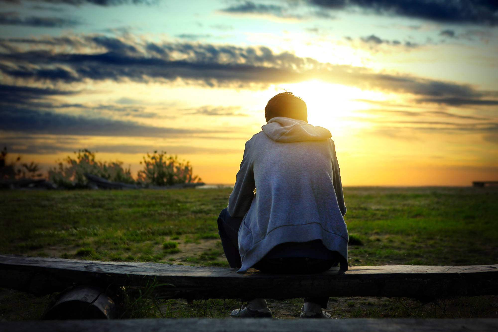 Young person sitting on the bench watching the sunset