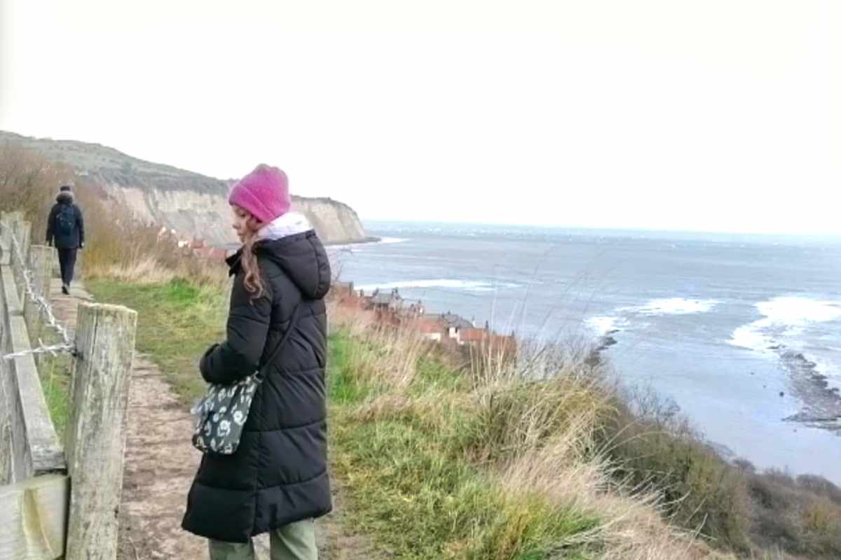 Girl walking by the sea in Robin Hood's Bay