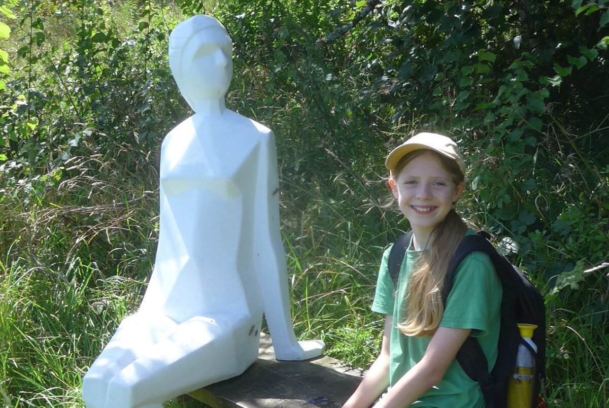 young girl sat with statue near YHA Coverack