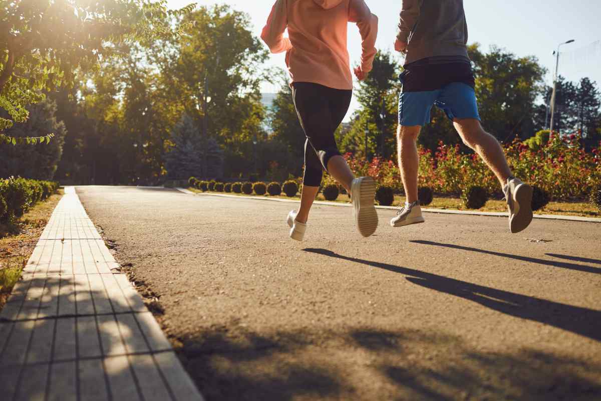 A man and a woman are running along the city street in the morning.