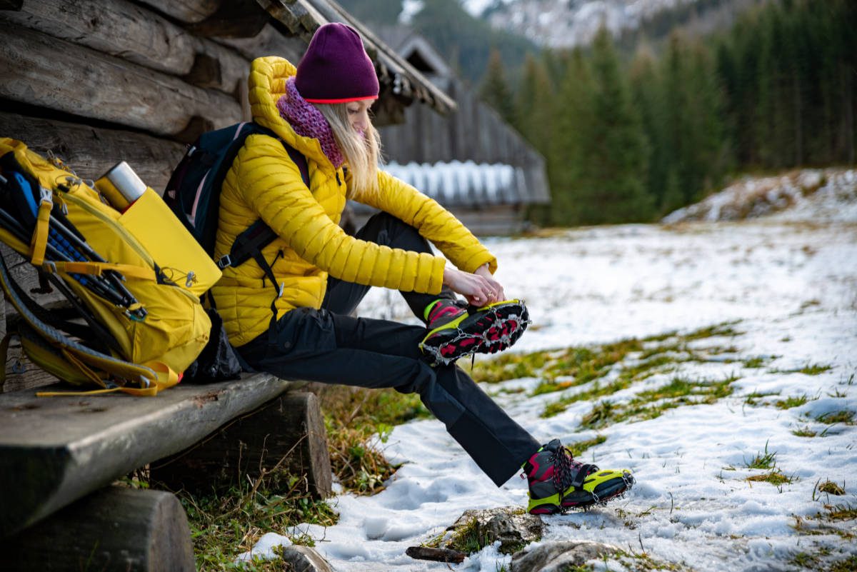 Woman preparing for a winter hike by putting on crampons